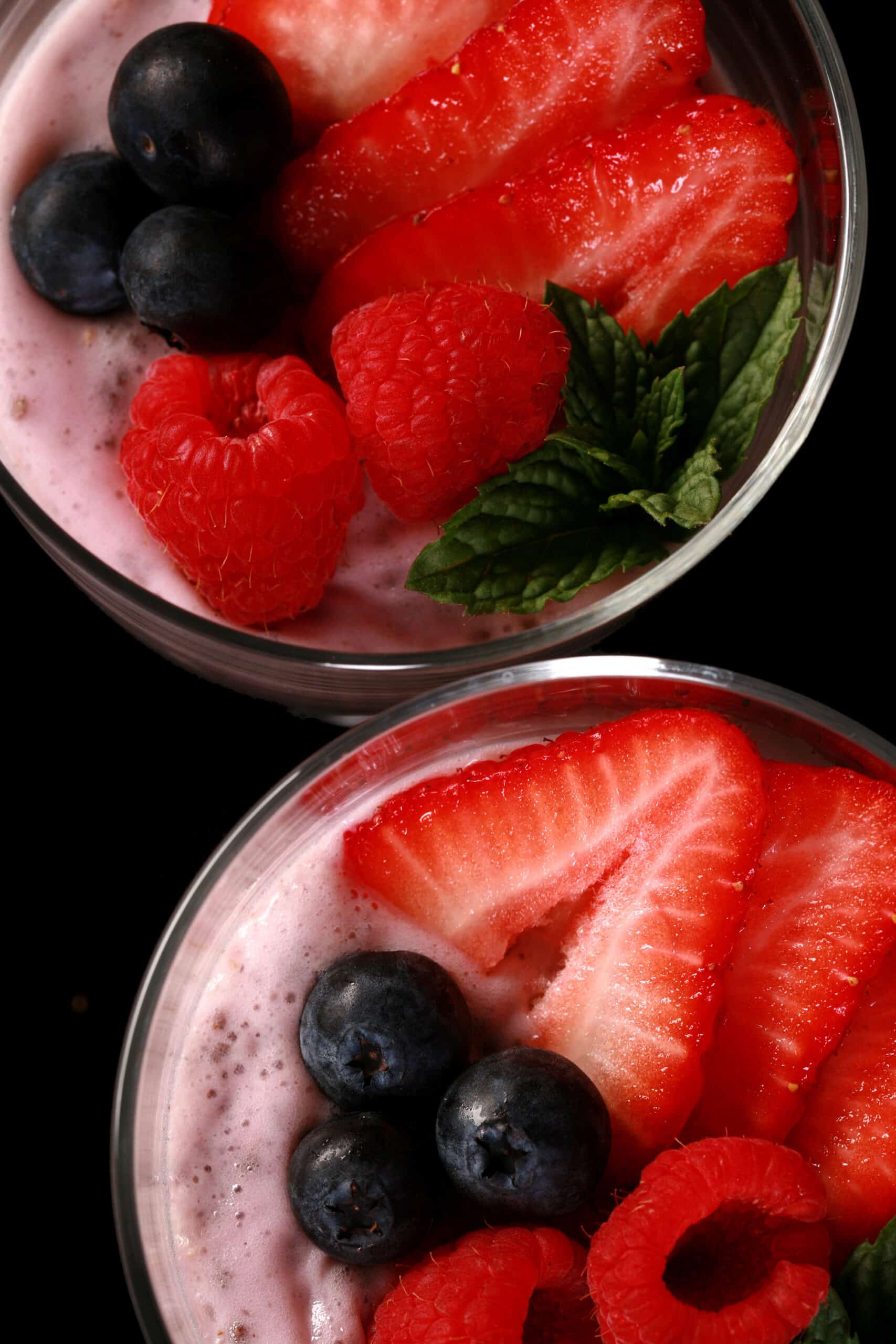 2 glasses of keto berry protein pudding, topped with strawberry slices, raspberries, and blueberries.