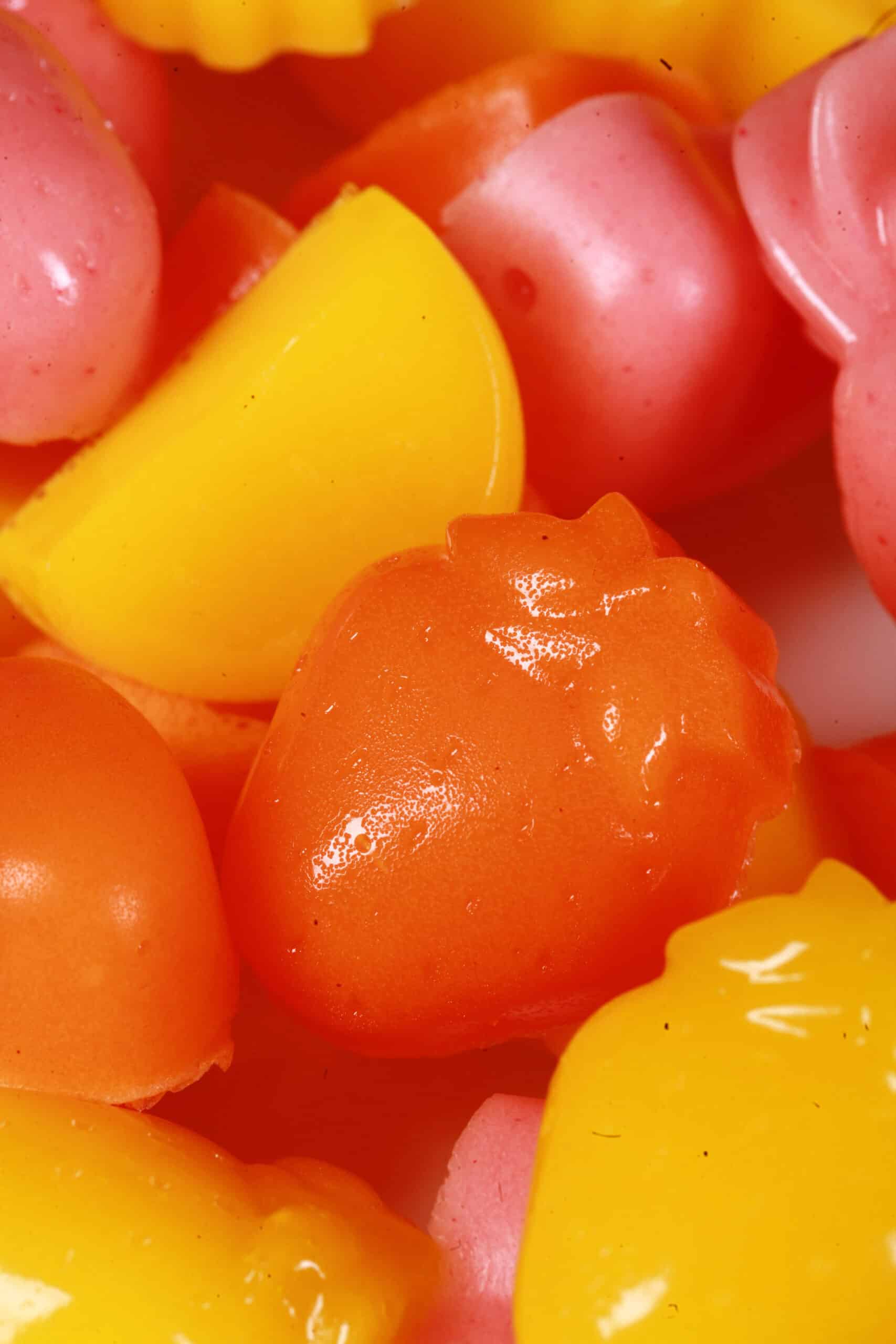 A plate of pink, orange, and yellow protein gummies in a variety of fruit and heart shapes.