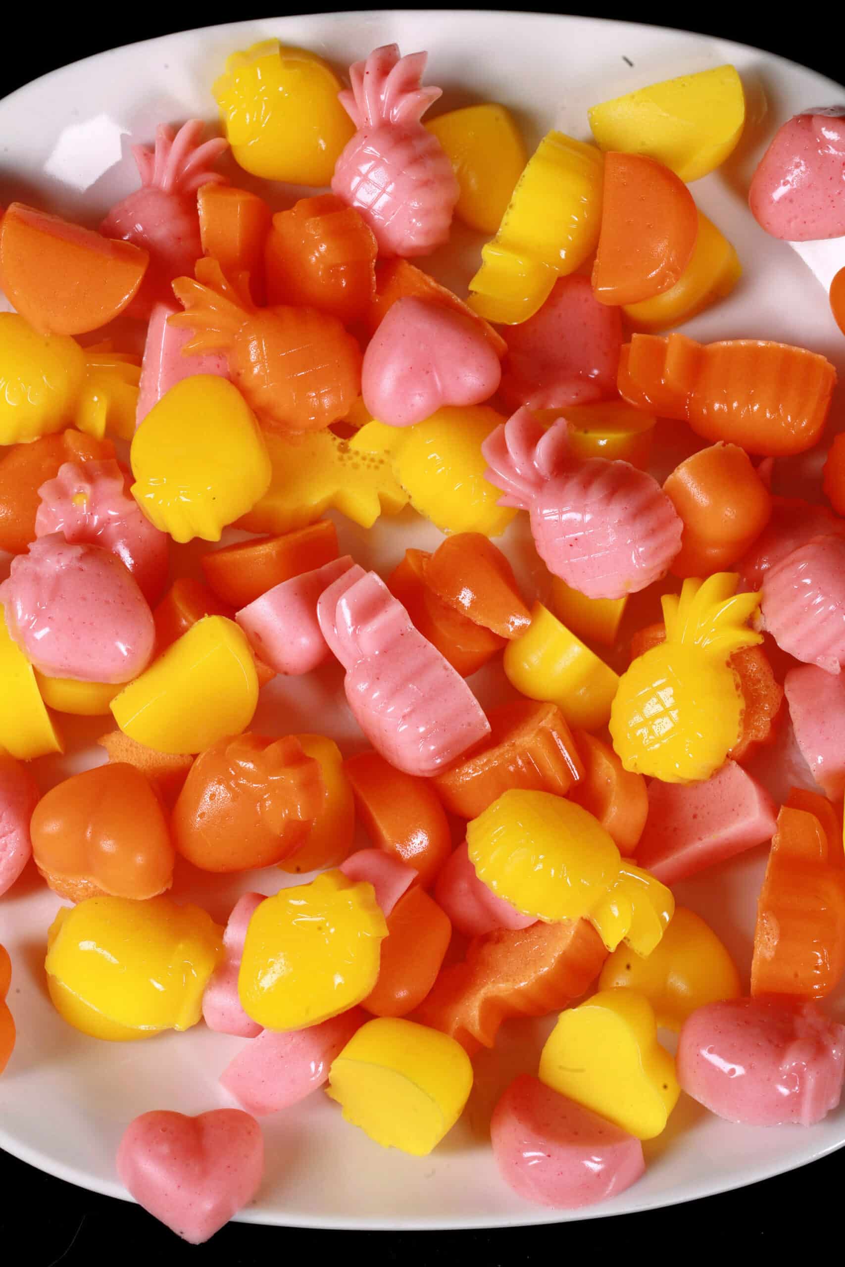 A plate of pink, orange, and yellow protein gummy candies in a variety of fruit and heart shapes.