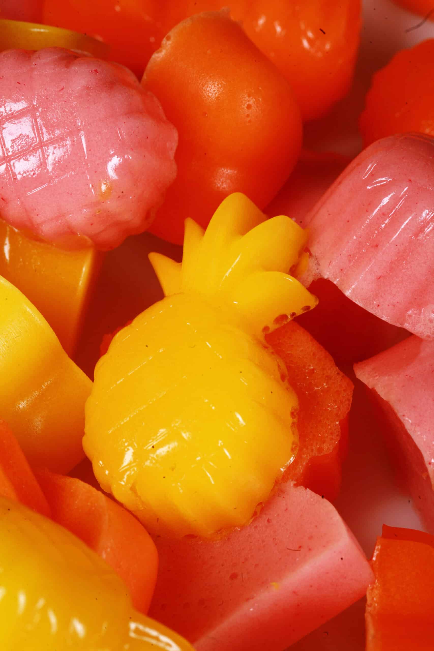A plate of pink, orange, and yellow protein gummies in a variety of fruit and heart shapes.