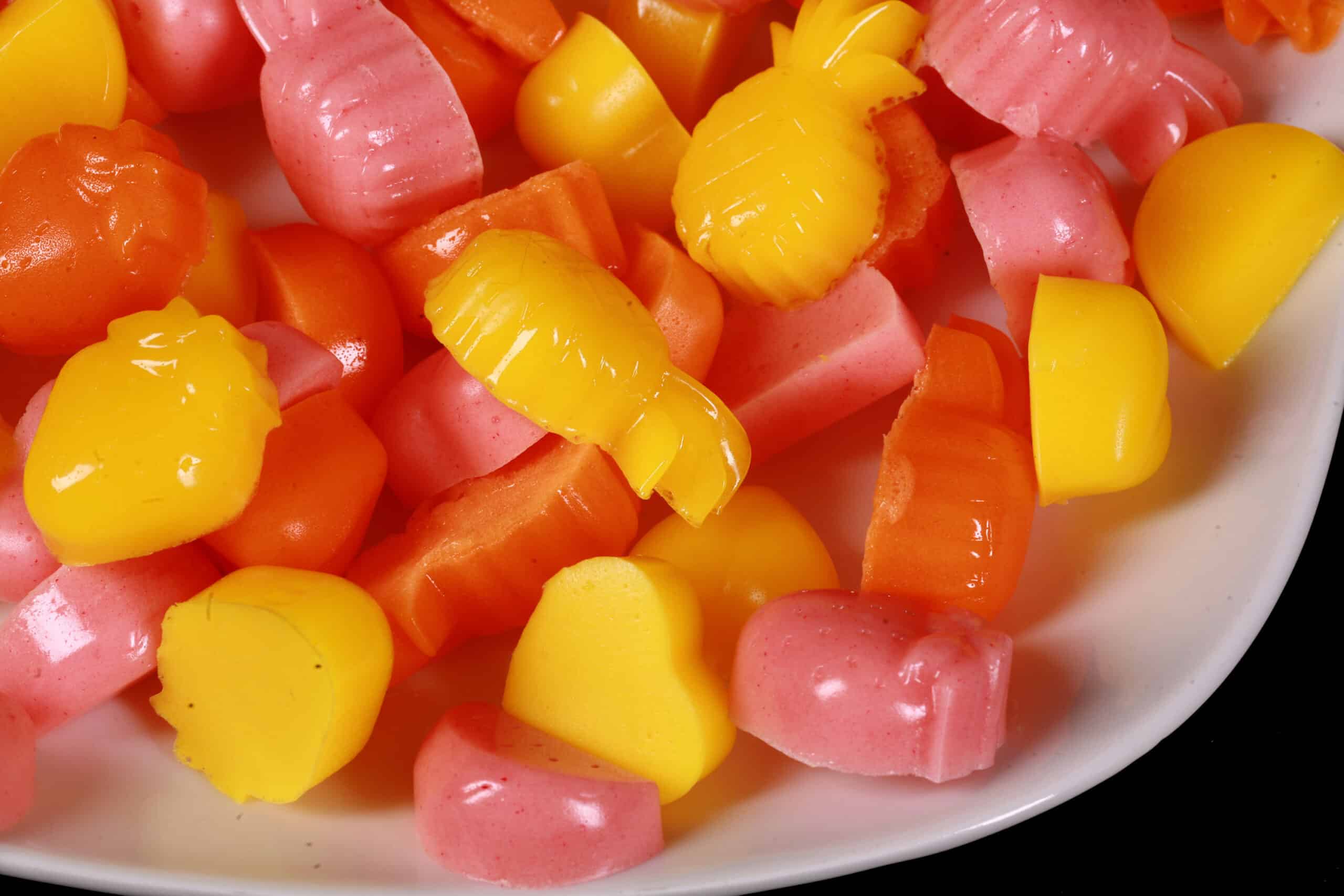 A plate of pink, orange, and yellow protein gummy candies in a variety of fruit and heart shapes.