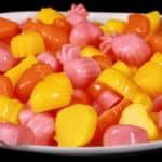 A plate of pink, orange, and yellow protein gummies in a variety of fruit and heart shapes.