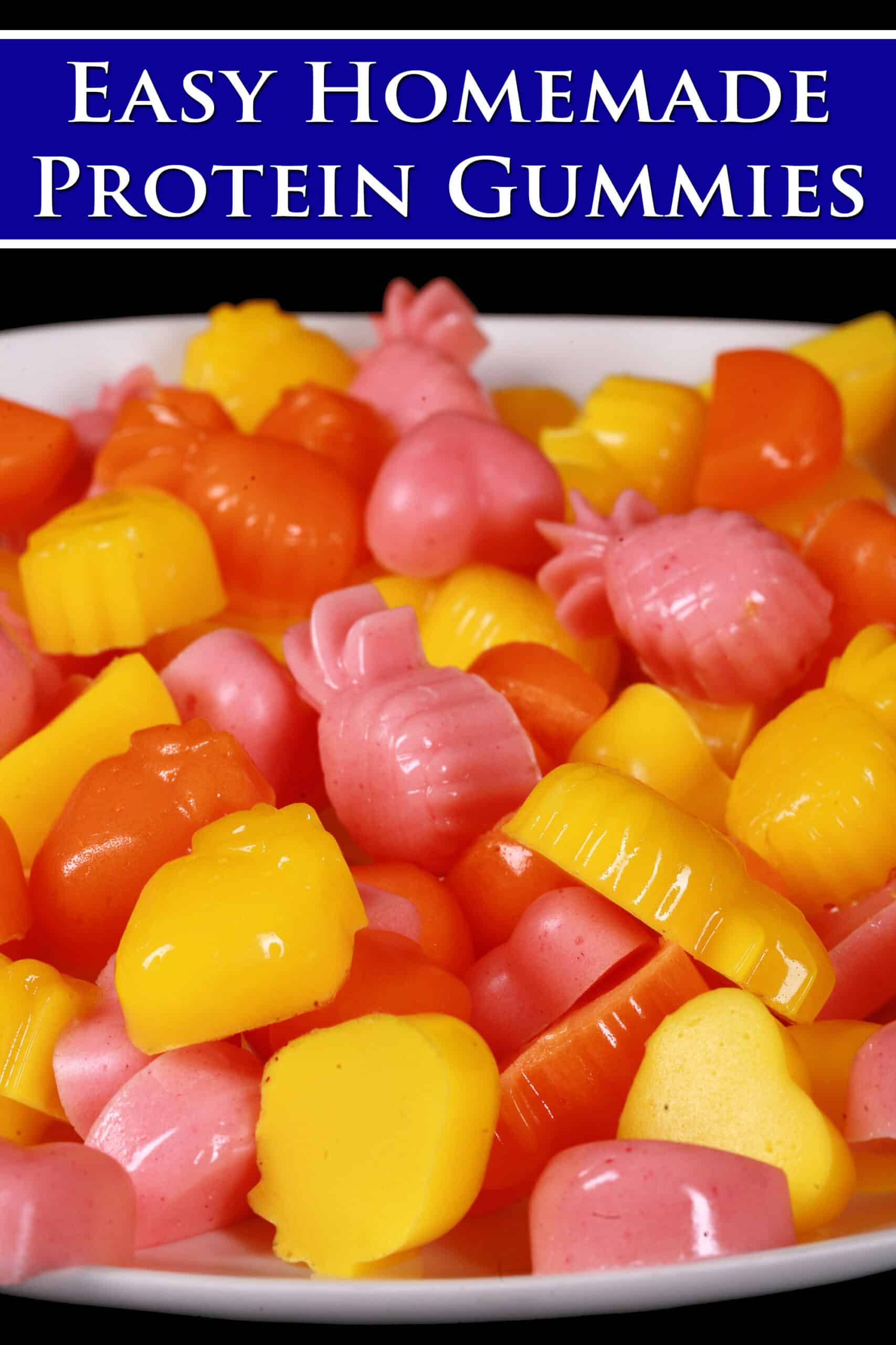 A plate of pink, orange, and yellow protein gummy candies in a variety of fruit and heart shapes. Overlaid text says easy homemade protein gummies.