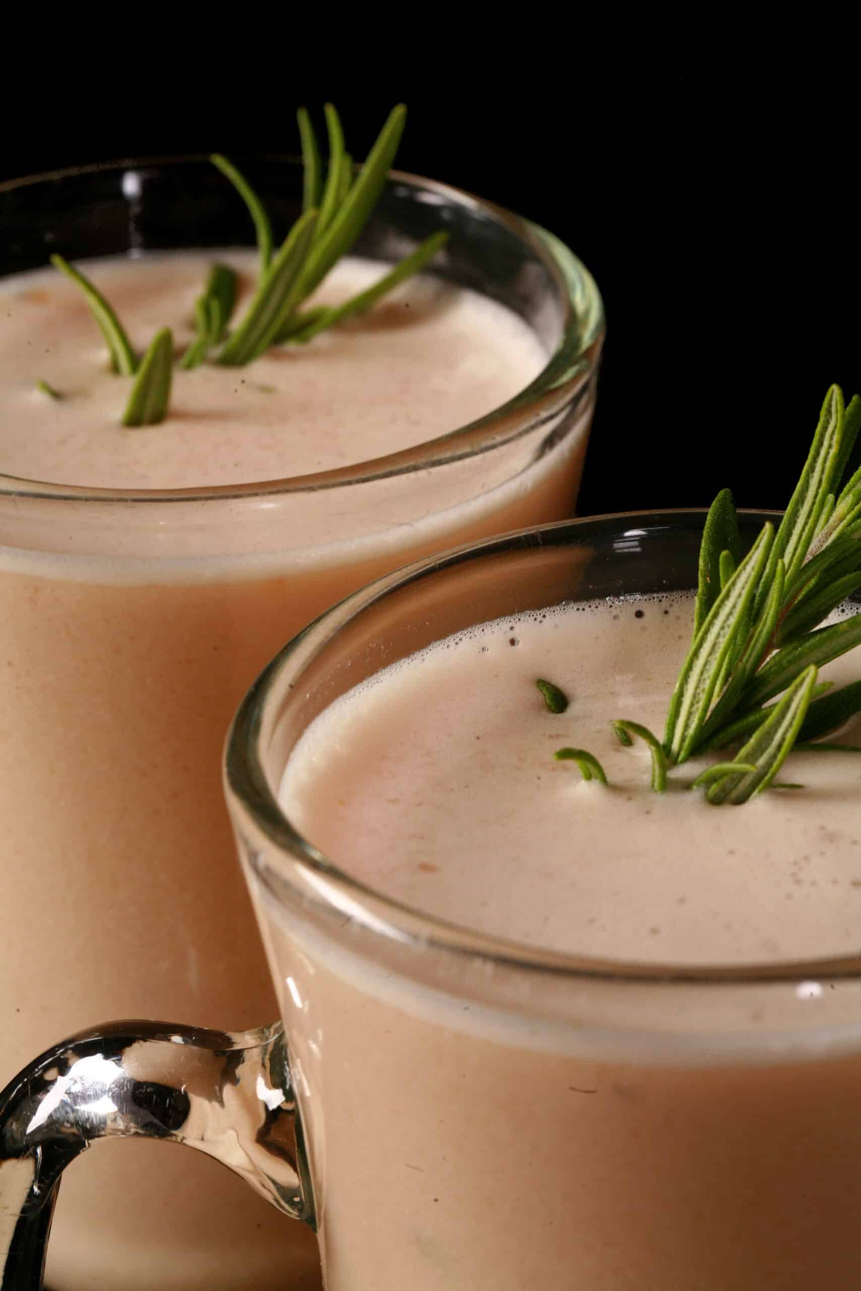 2 mugs of protein powder cream of chicken soup, garnished with rosemary sprigs.
