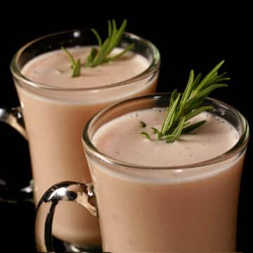 2 mugs of protein powder cream of chicken soup, garnished with rosemary sprigs.