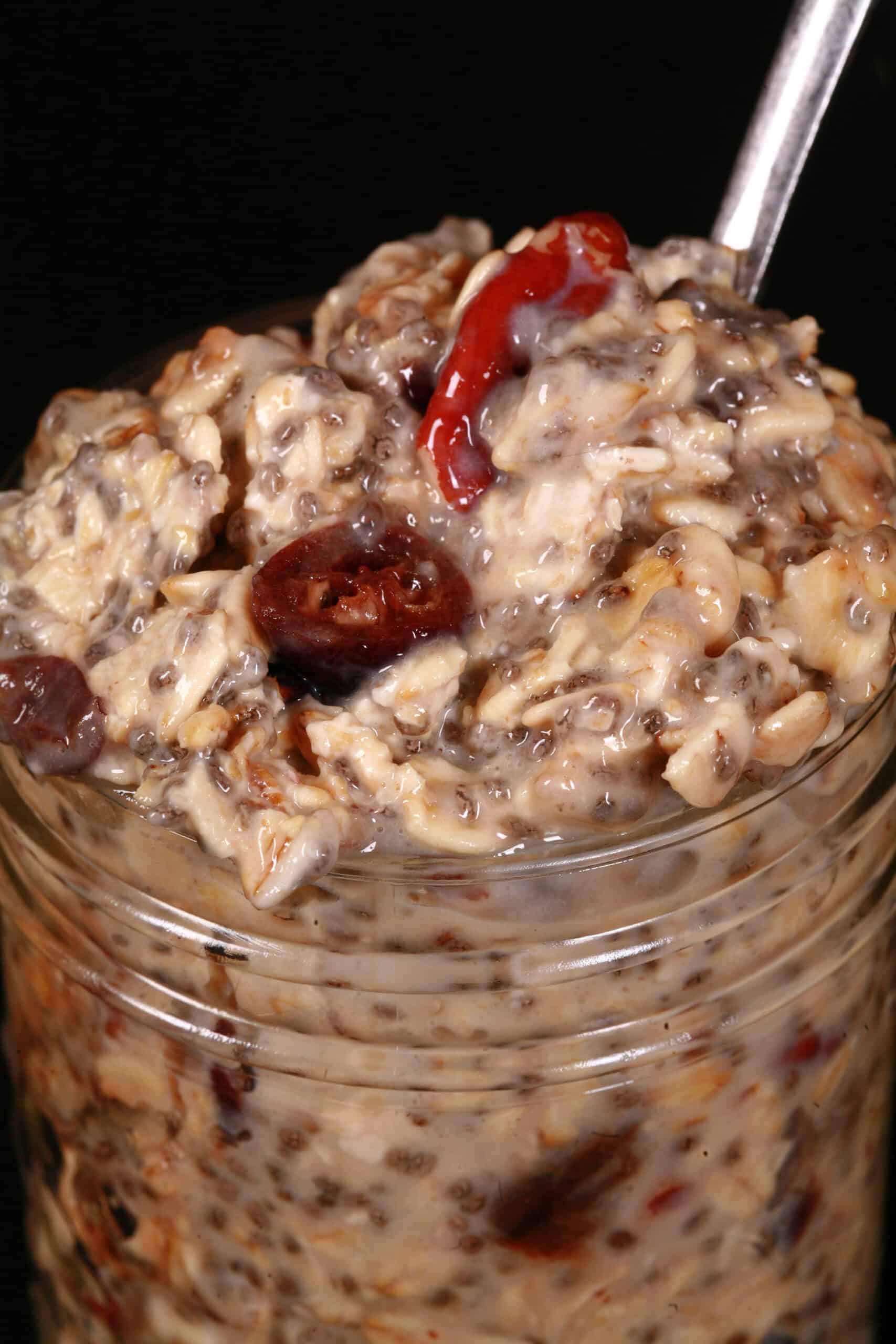 A jar of cranberry orange overnight oats, with dried cranberries and walnuts showing.