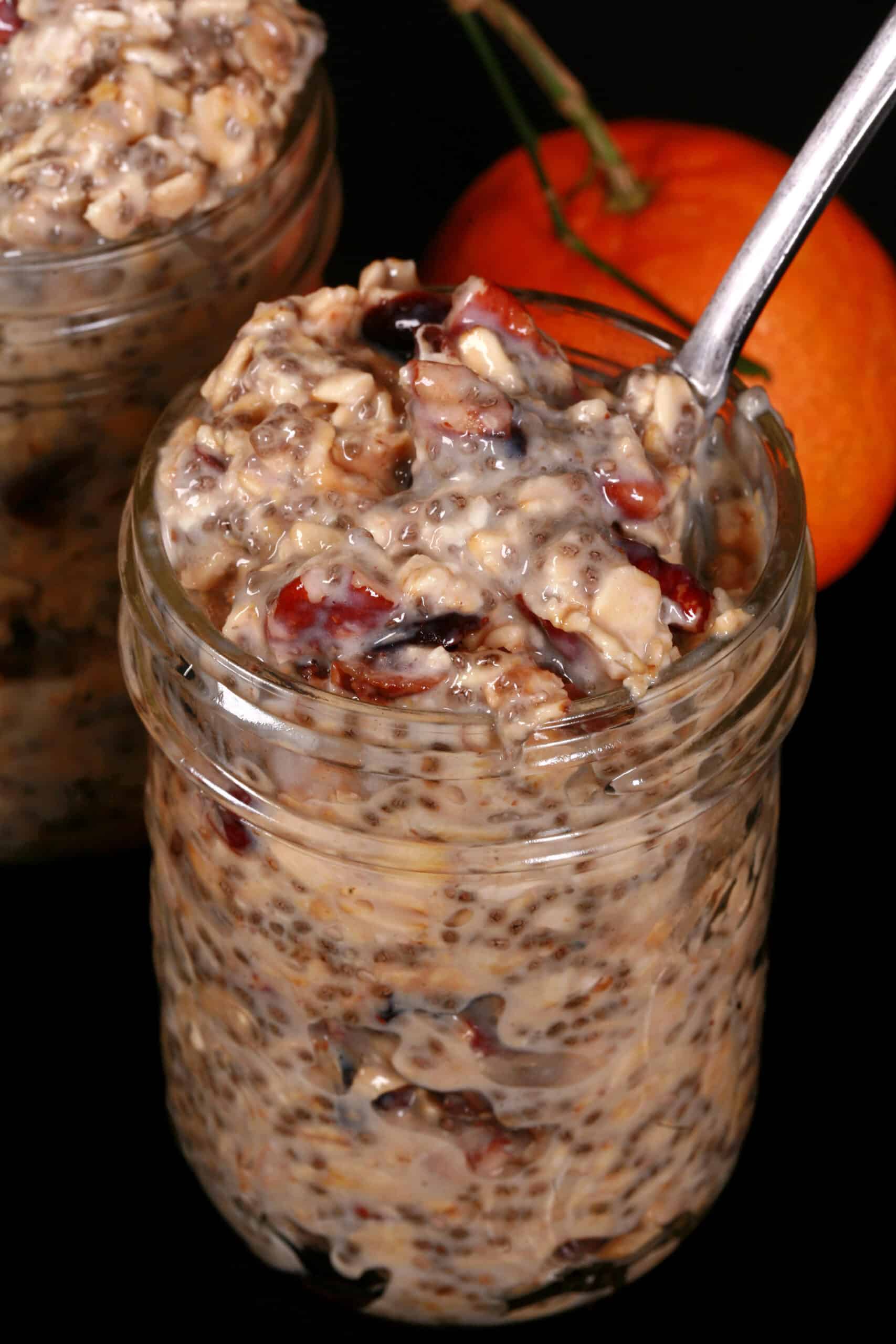 A jar of cranberry orange overnight oats, with dried cranberries and walnuts showing.