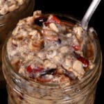 A jar of cranberry orange overnight oats, with dried cranberries and walnuts showing.