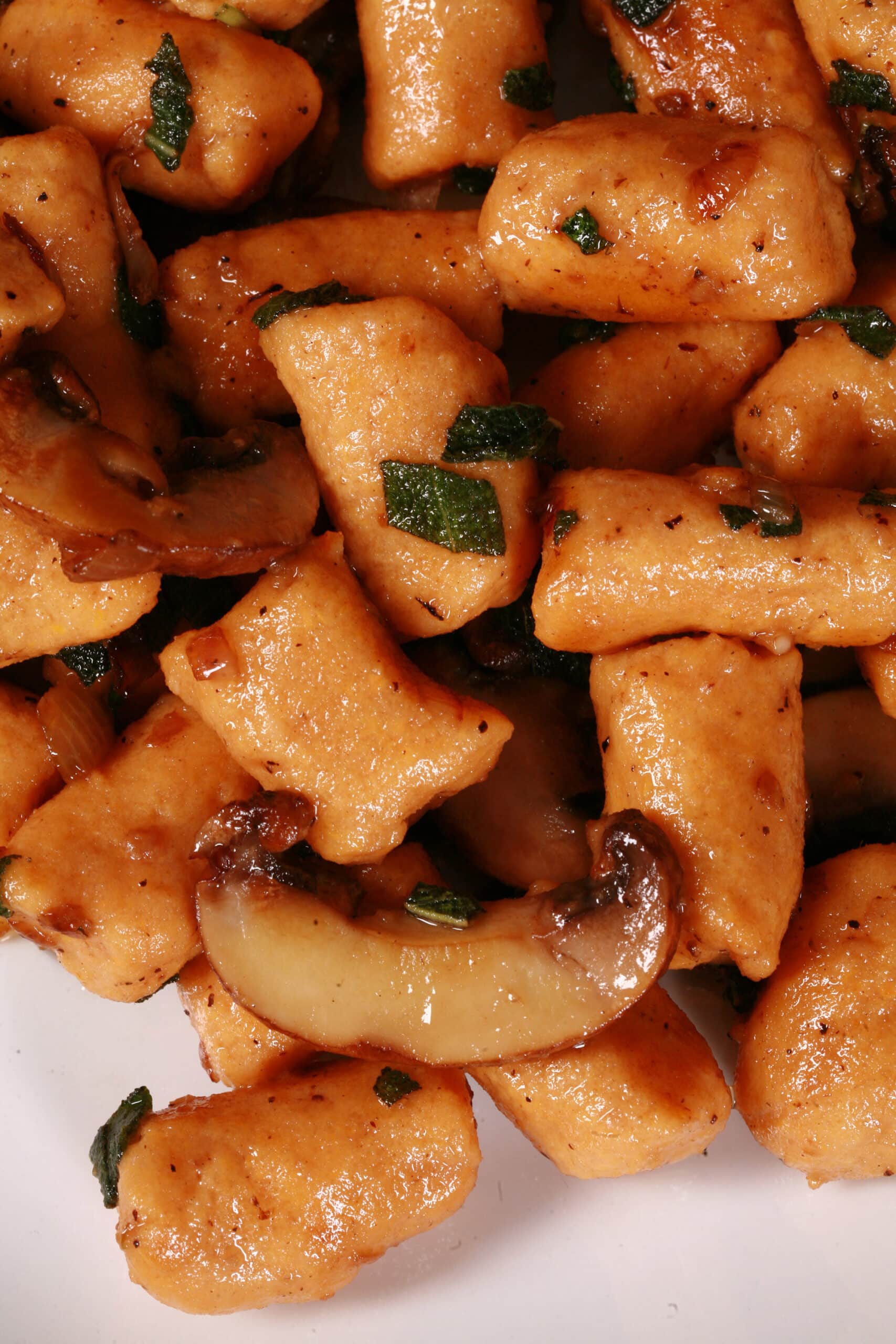 A plate of protein powder sweet potato gnocchi with sauteed mushrooms and sage.
