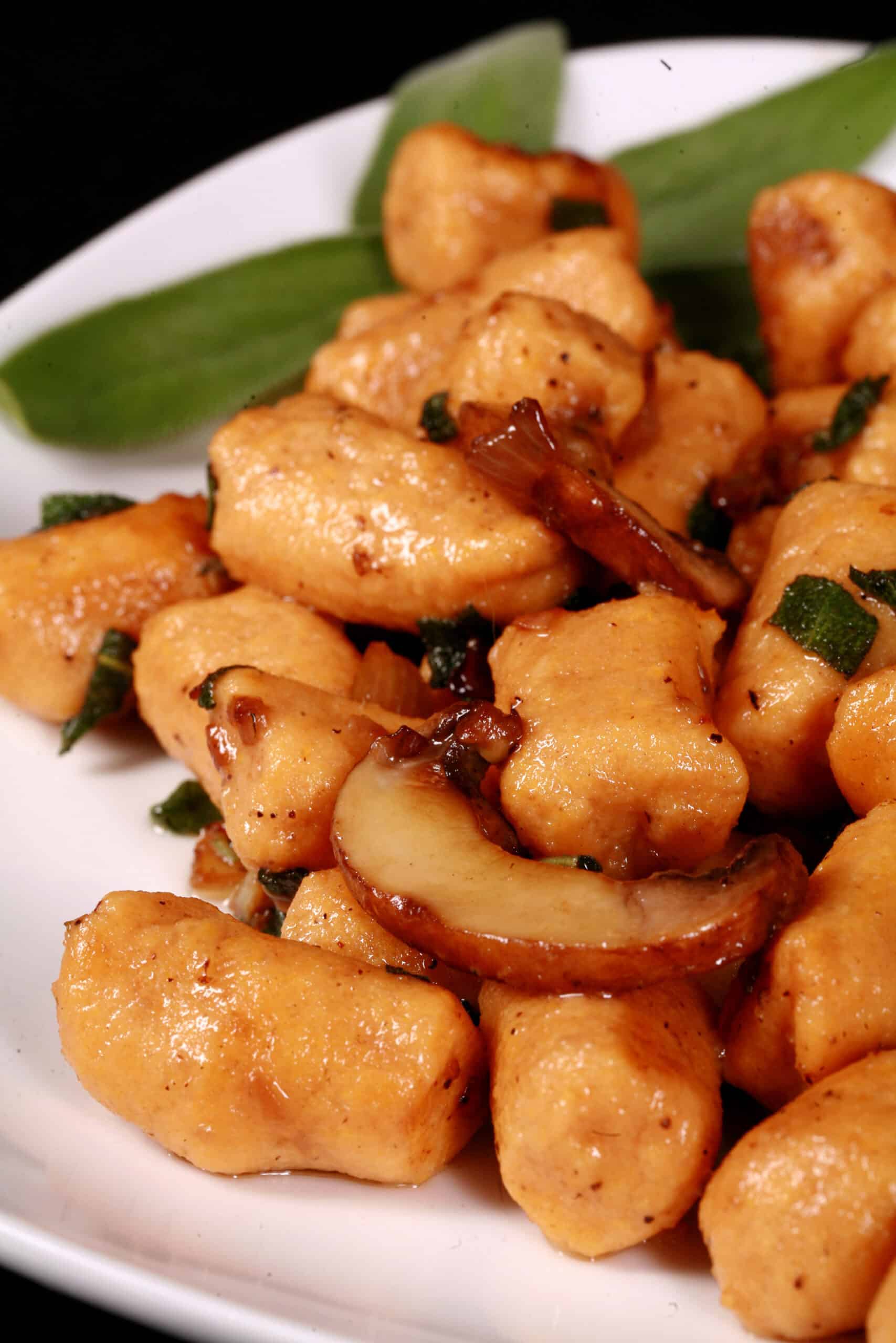 A plate of high protein sweet potato gnocchi with sauteed mushrooms and sage.
