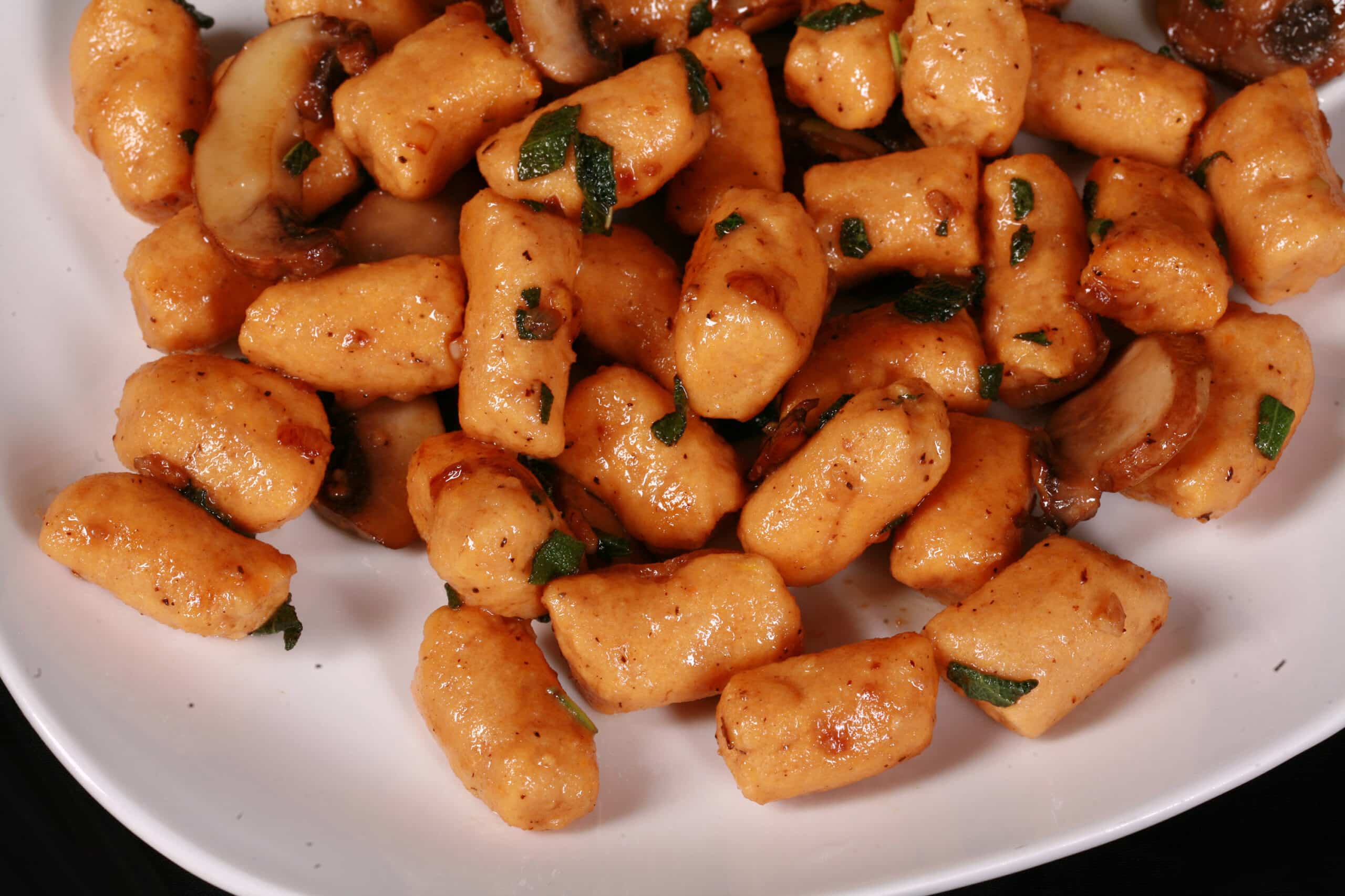 A plate of high protein sweet potato gnocchi with sauteed mushrooms and sage.