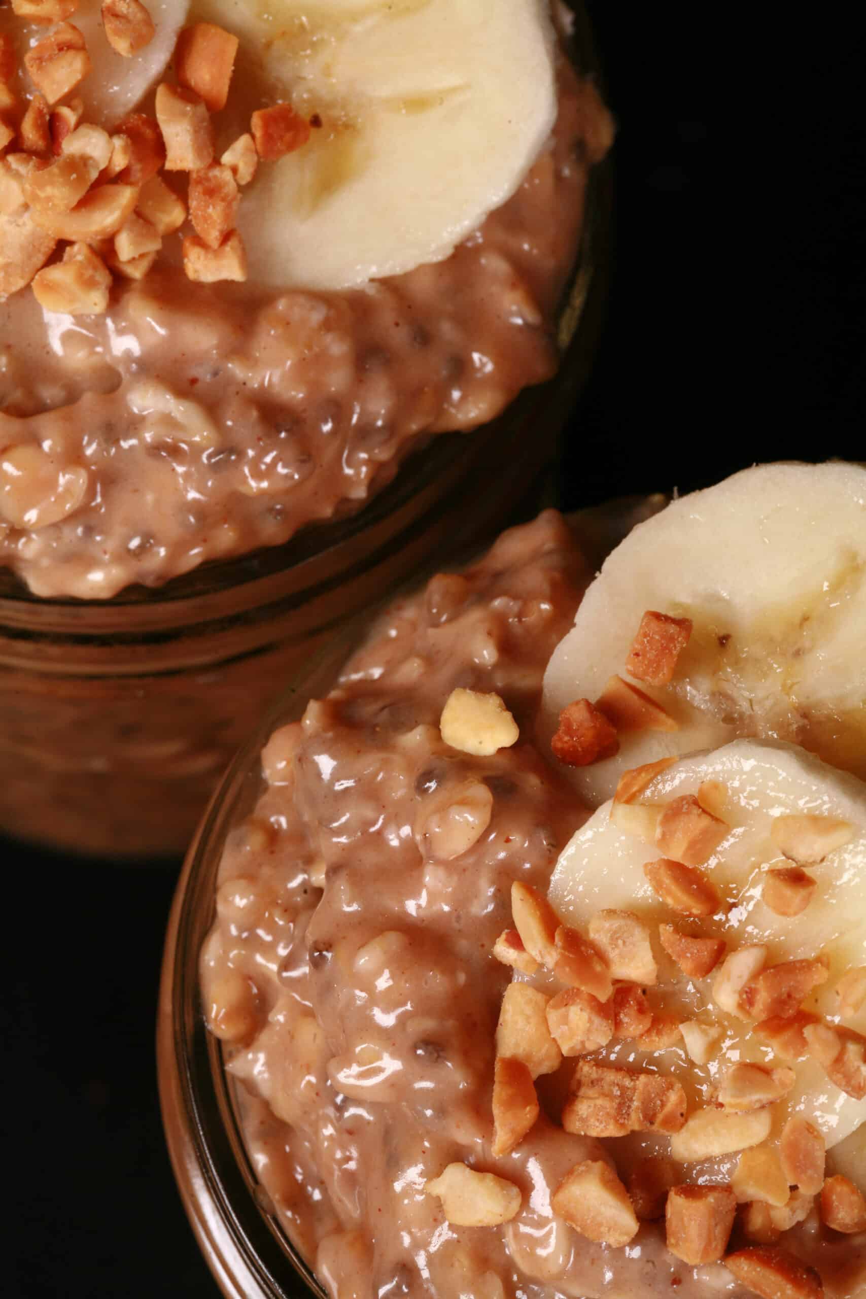 2 jars of high protein peanut butter and banana overnight oatmeal, garnished with banana slices and chopped peanuts.