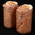 2 jars of high protein peanut butter and banana overnight oatmeal, garnished with banana slices and chopped peanuts.