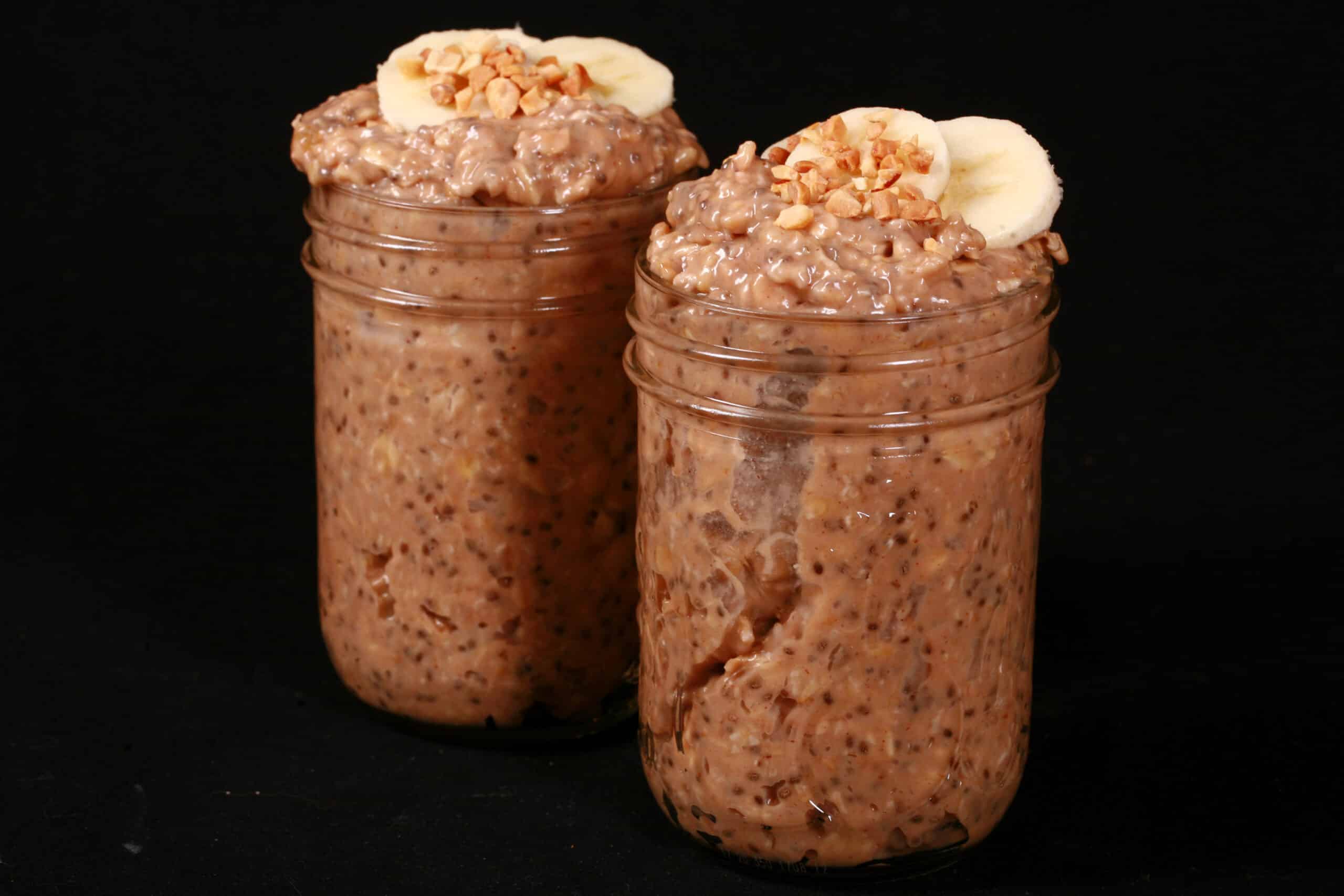 2 jars of high protein peanut butter and banana overnight oatmeal, garnished with banana slices and chopped peanuts.