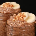 2 jars of high protein peanut butter and banana overnight oats, garnished with banana slices and chopped peanuts.
