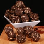 A bowl of peanut butter cup protein balls, with more on the cutting board it's sitting on.