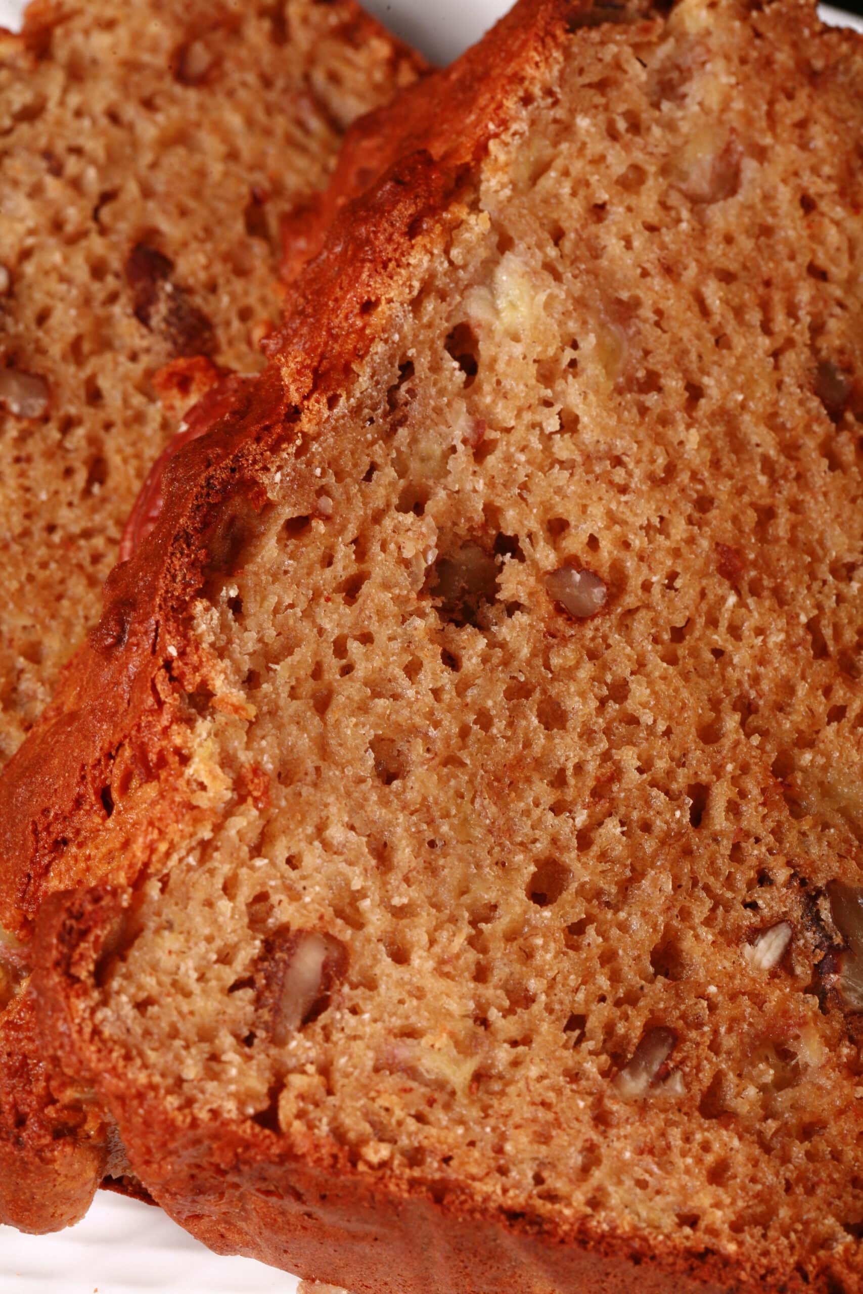 A sliced loaf of gluten free high protein banana nut bread on a white plate.
