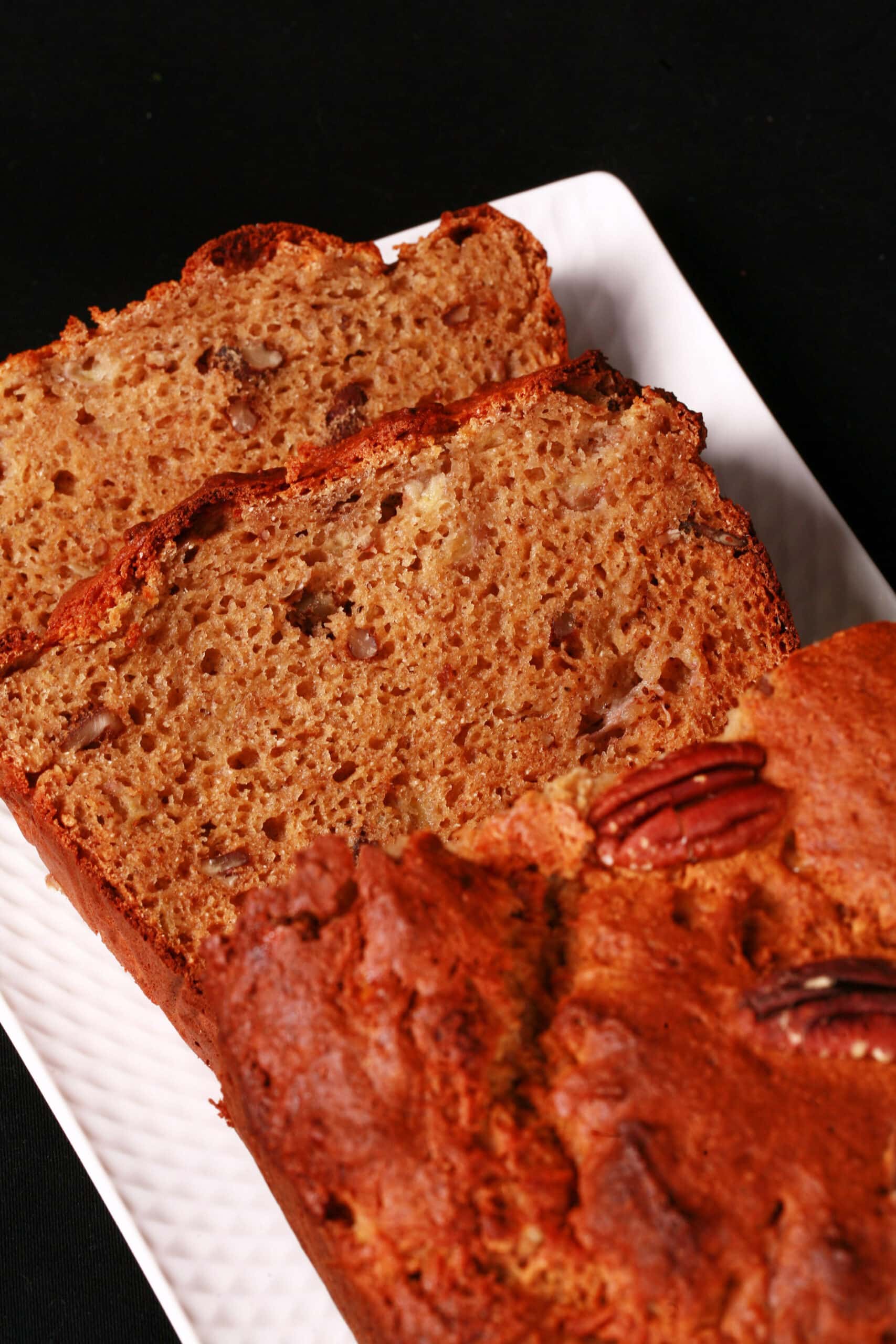 A sliced loaf of gluten free high protein banana bread on a white plate.