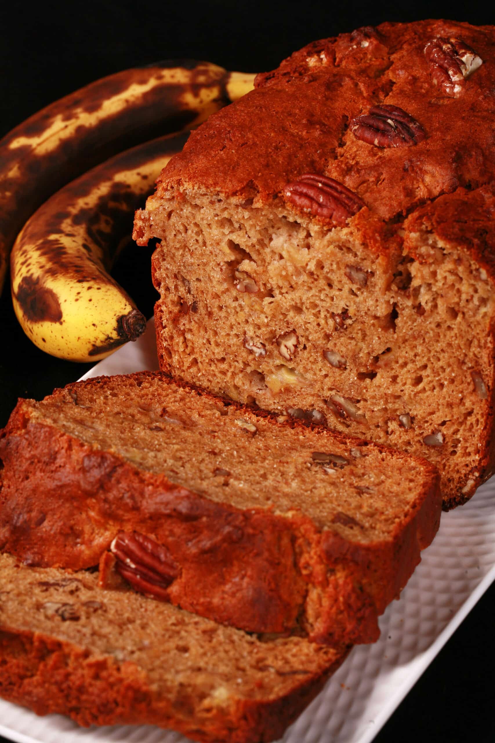 A sliced loaf of gluten free high protein banana bread on a white plate.