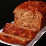 A sliced loaf of gluten free high protein banana bread on a white plate.