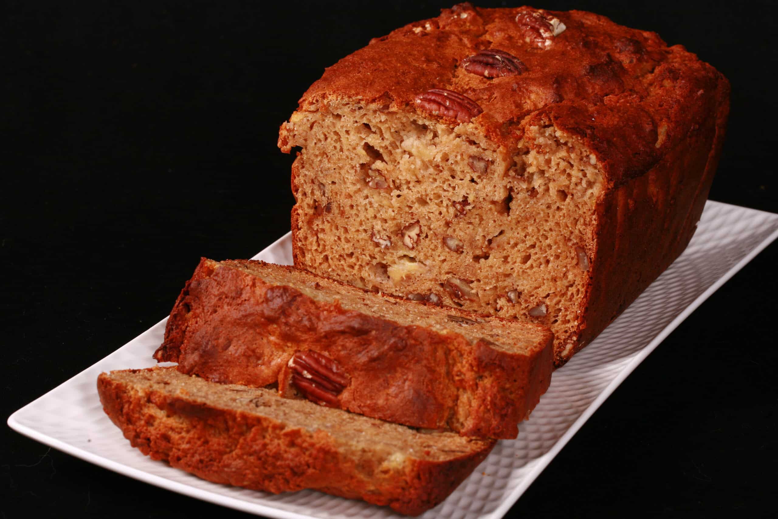 A sliced loaf of gluten free high protein banana bread on a white plate.