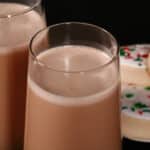 2 tall glasses of sugar cookie flavoured protein coffee shake, with frosted sugar cookies on a plate next to them.