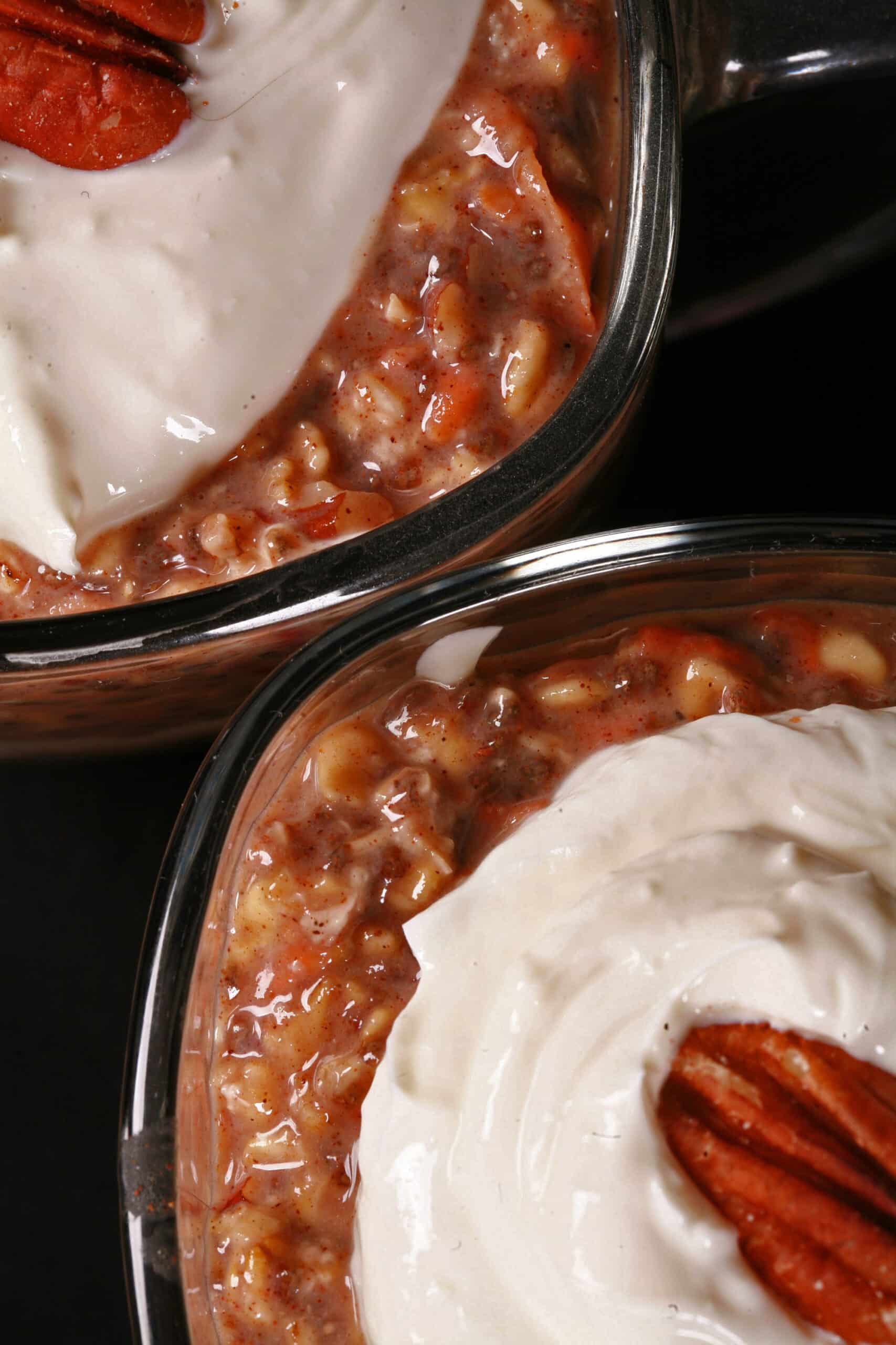 2 glasses of high protein carrot cake overnight oatmeal parfaits, with layers of cream cheese and Greek Yogurt.