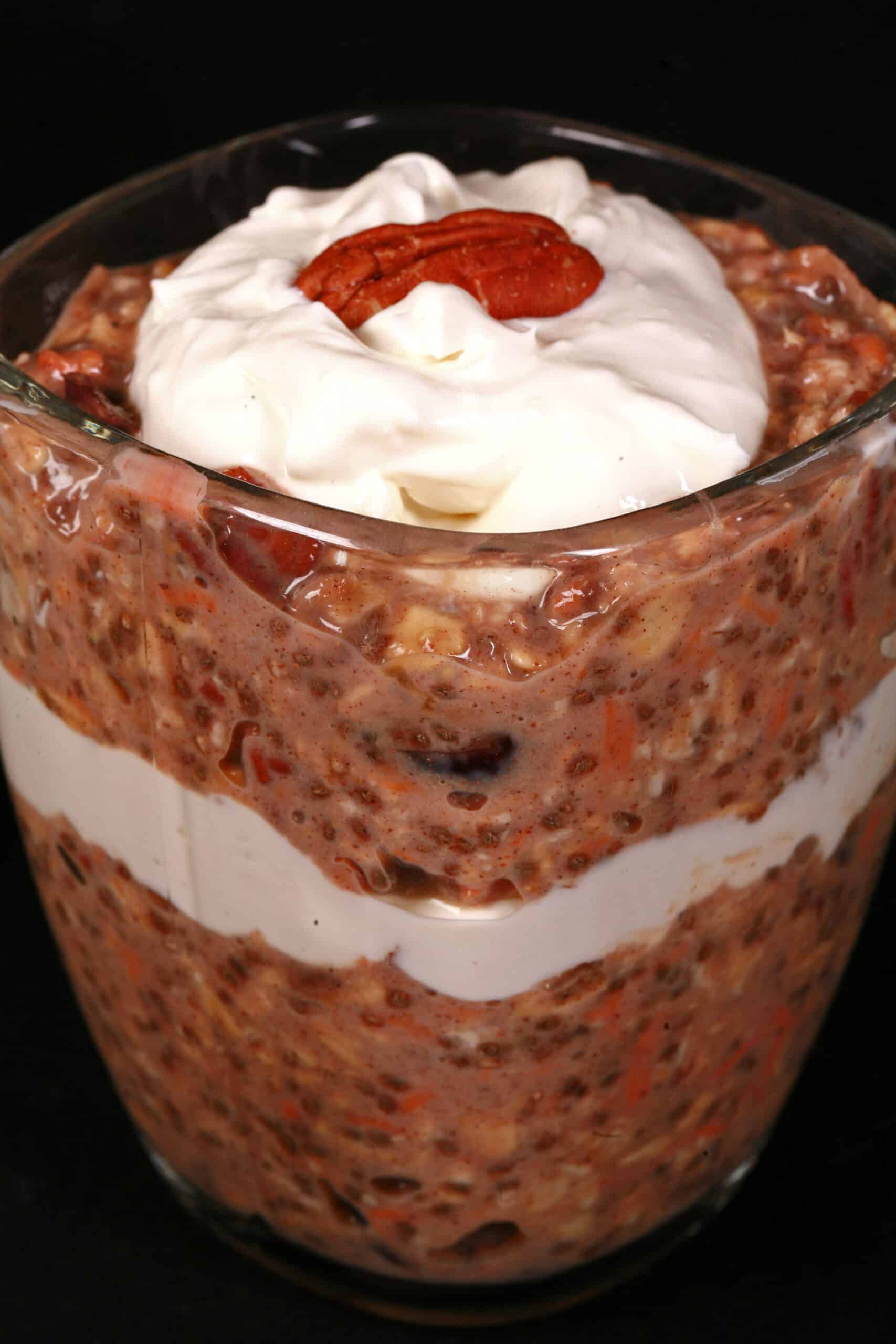 2 glasses of high protein carrot cake overnight oats parfaits, with layers of cream cheese and Greek Yogurt.