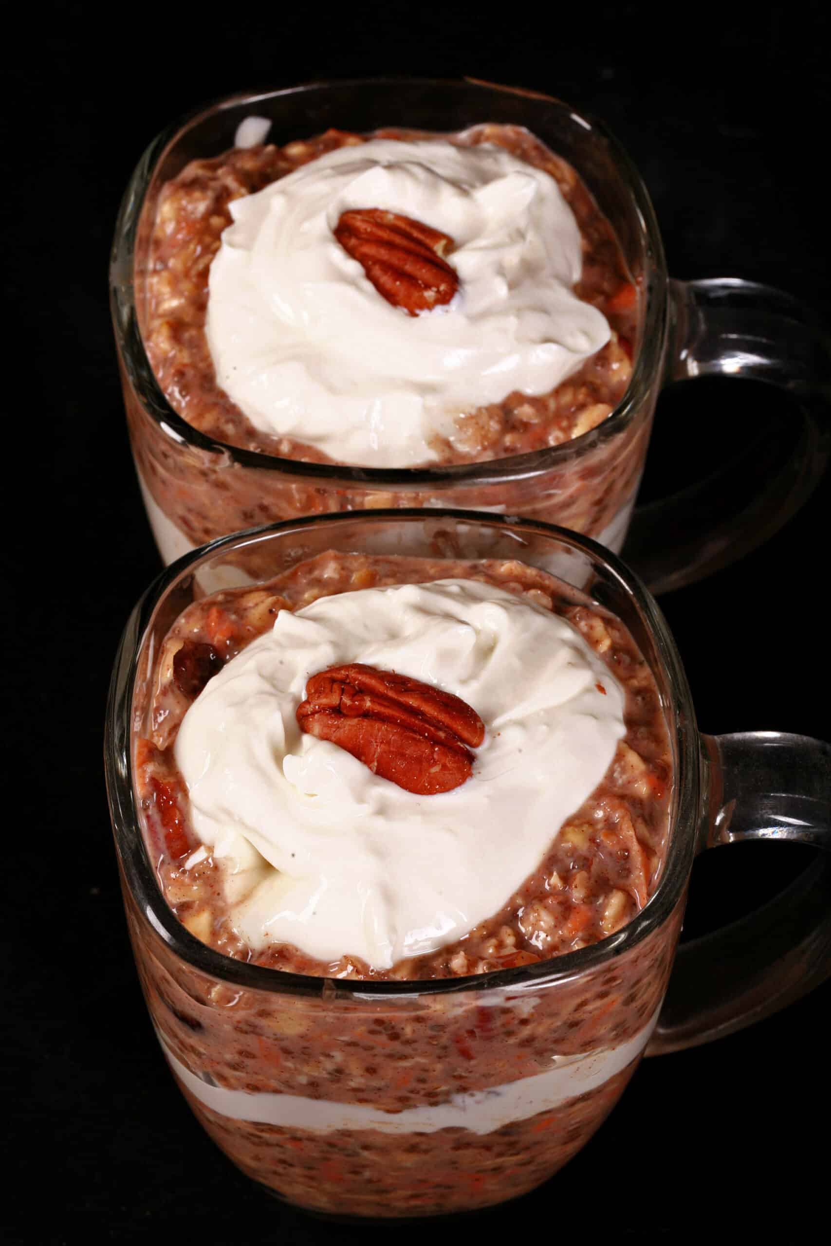 2 glasses of high protein carrot cake overnight oatmeal parfaits, with layers of cream cheese and Greek Yogurt.