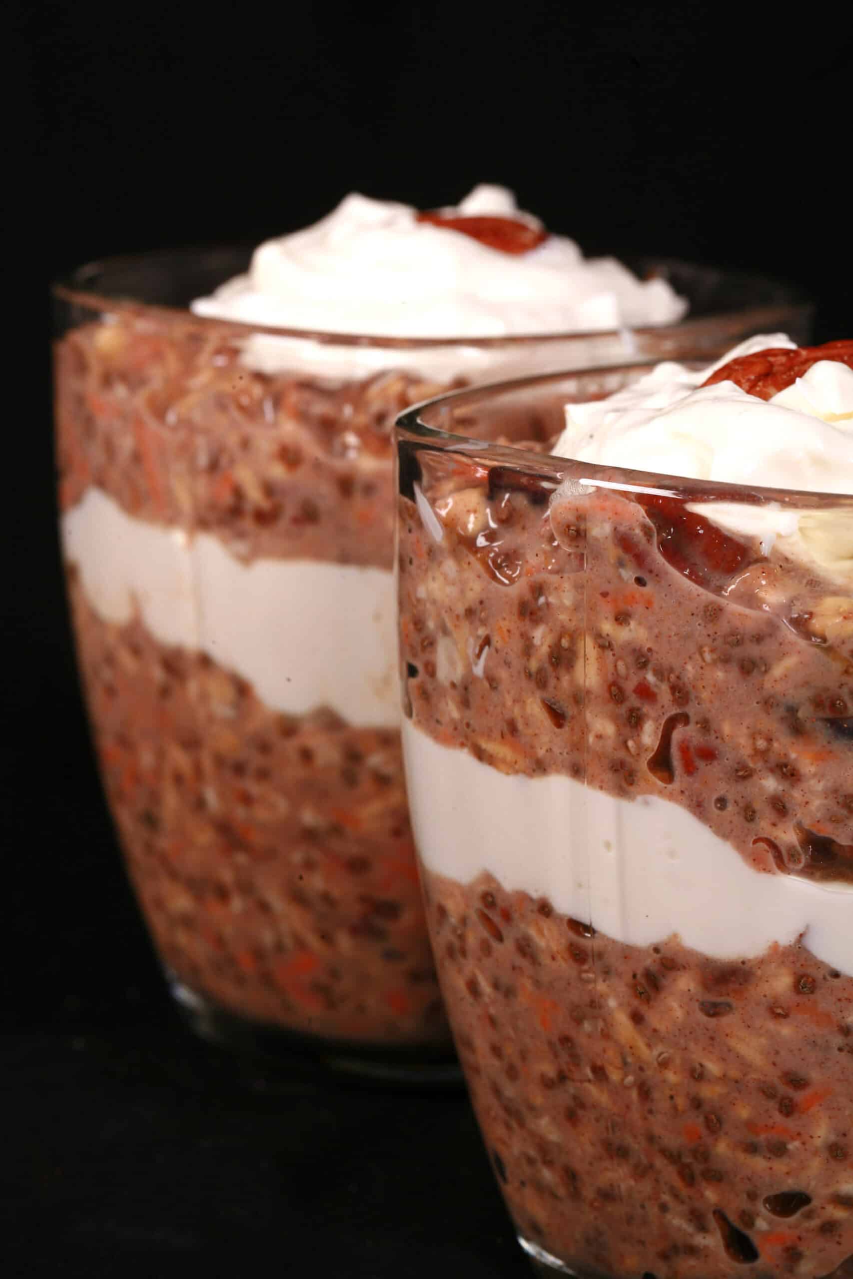 2 glasses of high protein carrot cake overnight oats parfaits, with layers of cream cheese and Greek Yogurt.