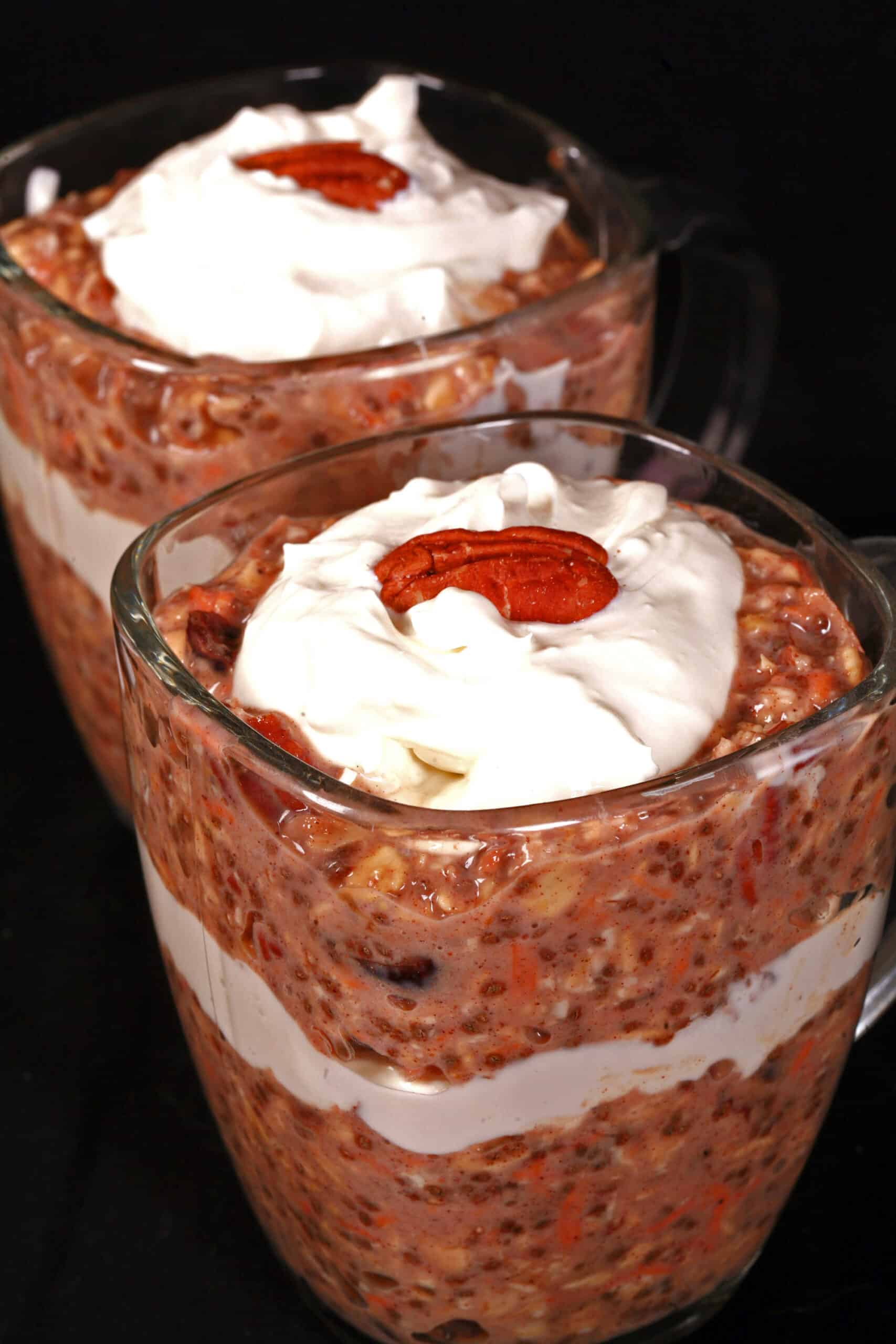 2 glasses of high protein carrot cake overnight oatmeal parfaits, with layers of cream cheese and Greek Yogurt.