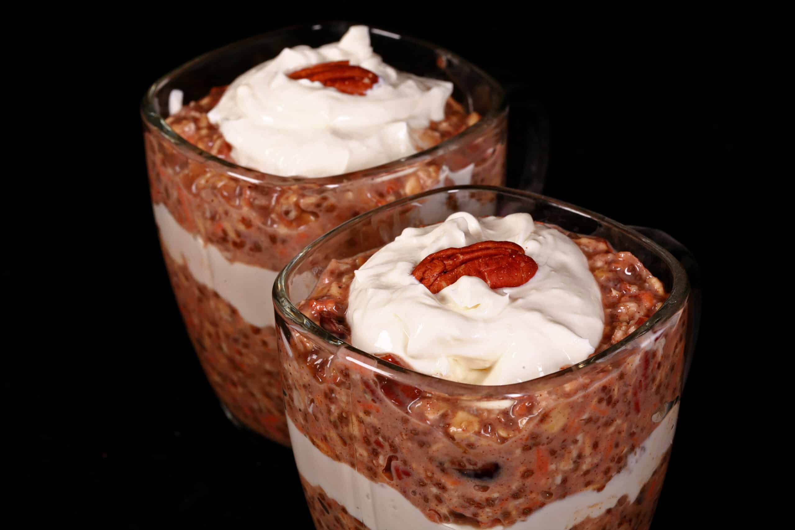 2 glasses of high protein carrot cake overnight oats parfaits, with layers of cream cheese and Greek Yogurt.