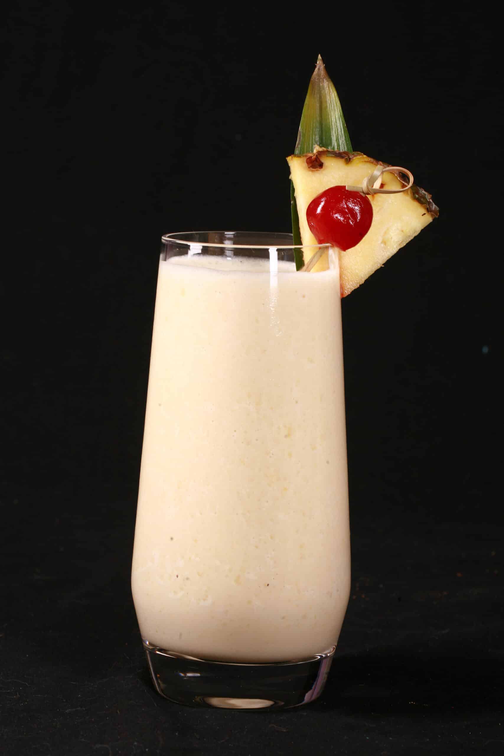 A High Protein Pina Colada Smoothie garnished with a pineapple wedge and cherry.