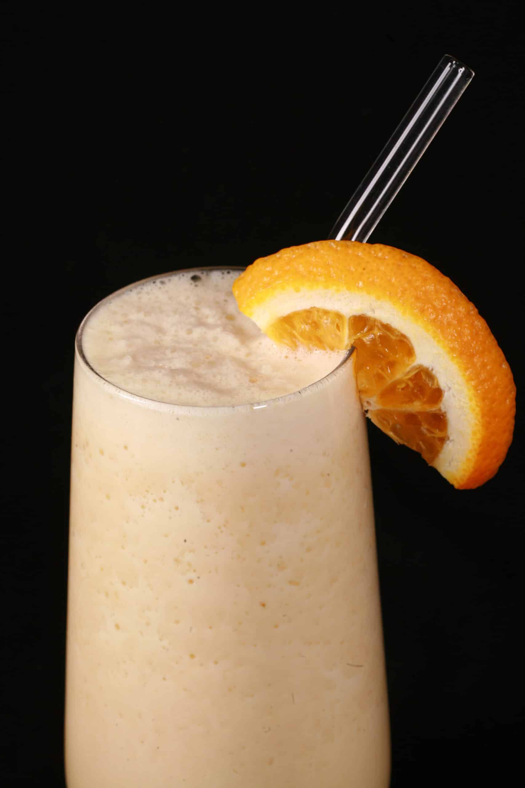 A high protein Orange Julius smoothie, garnished with a fresh orange slice.