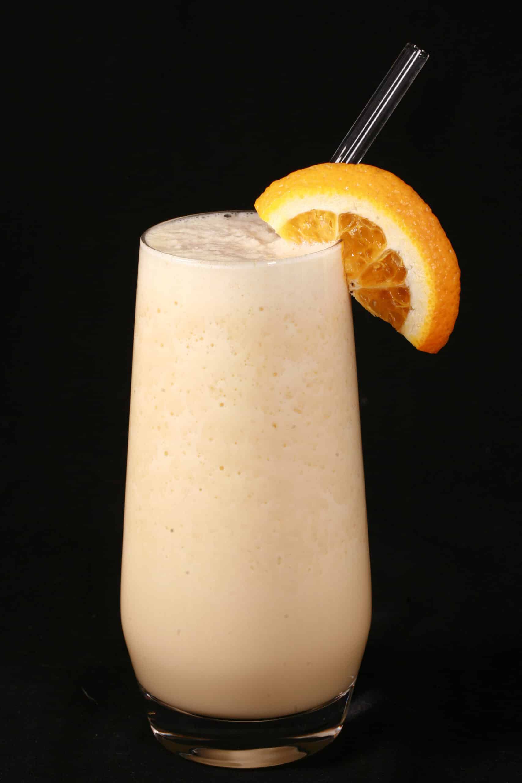 A high protein Orange Julius smoothie, garnished with a fresh orange slice.