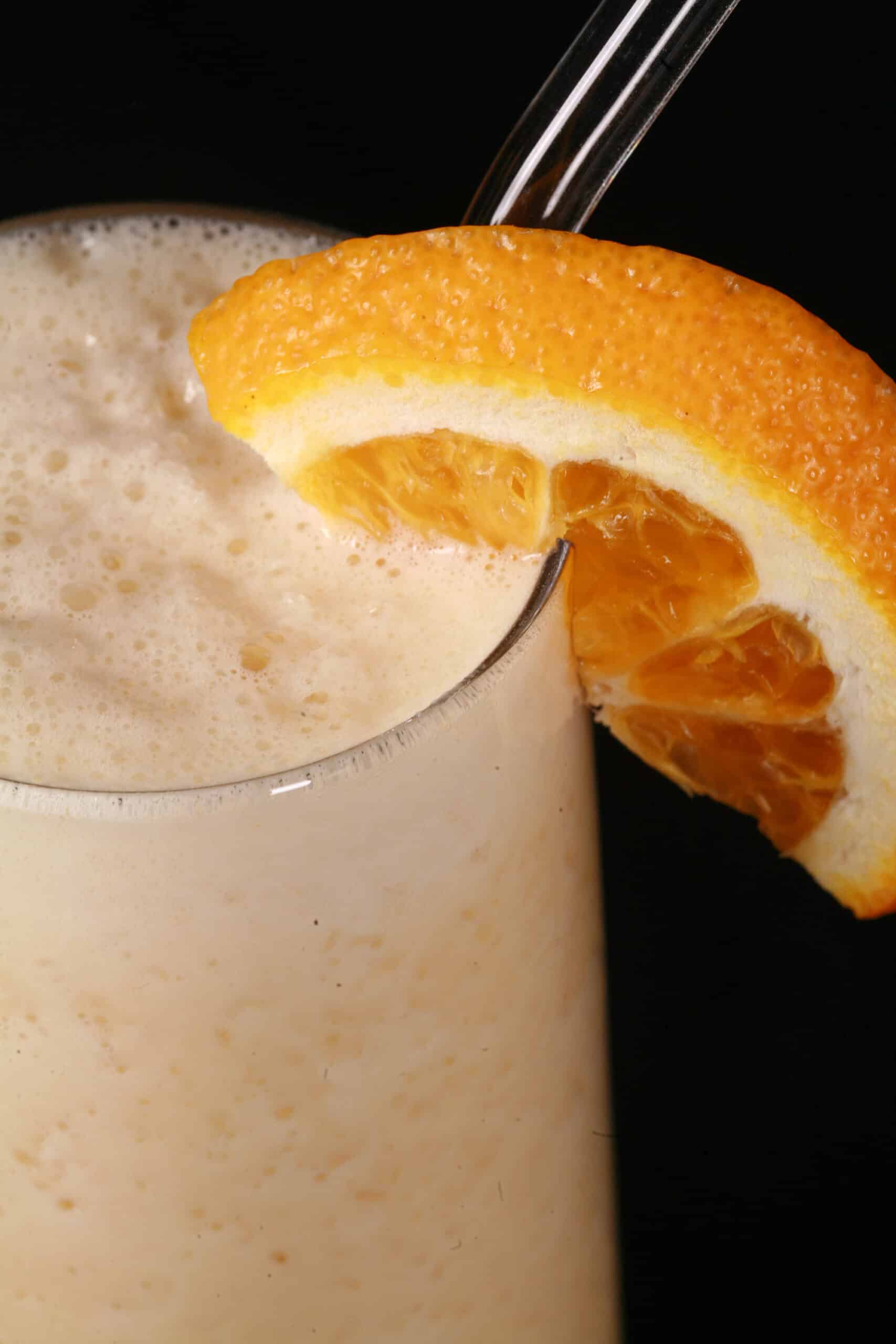 A high protein Orange Julius smoothie, garnished with a fresh orange slice.