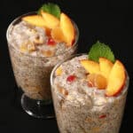 2 dessert glasses of high protein peach ginger chia pudding, garnished with peach slices, mint, and candied ginger.