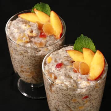 2 dessert glasses of high protein peach ginger chia pudding, garnished with peach slices, mint, and candied ginger.