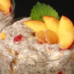 2 dessert glasses of high protein ginger peach chia pudding, garnished with peach slices, mint, and candied ginger.