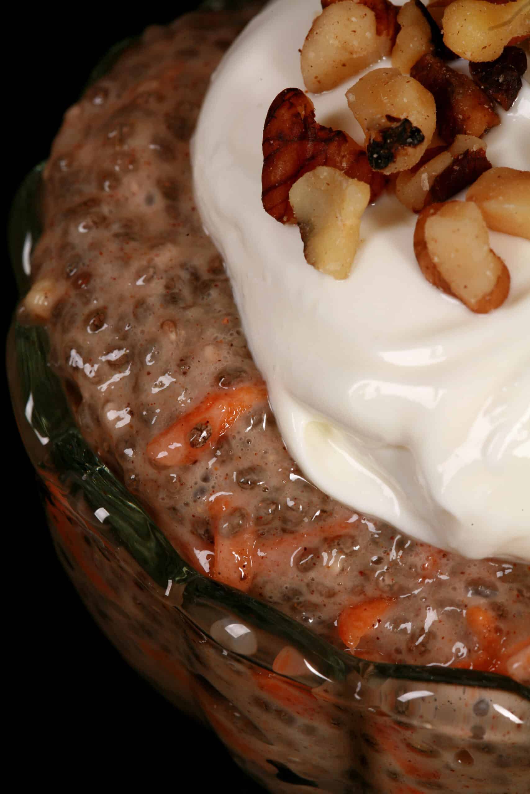 2 dessert cups of high protein carrot cake chia pudding, topped with cream cheese Greek yogurt topping and chopped walnuts.