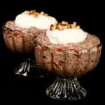 2 dessert cups of high protein carrot cake chia pudding, topped with cream cheese Greek yogurt topping and chopped walnuts.