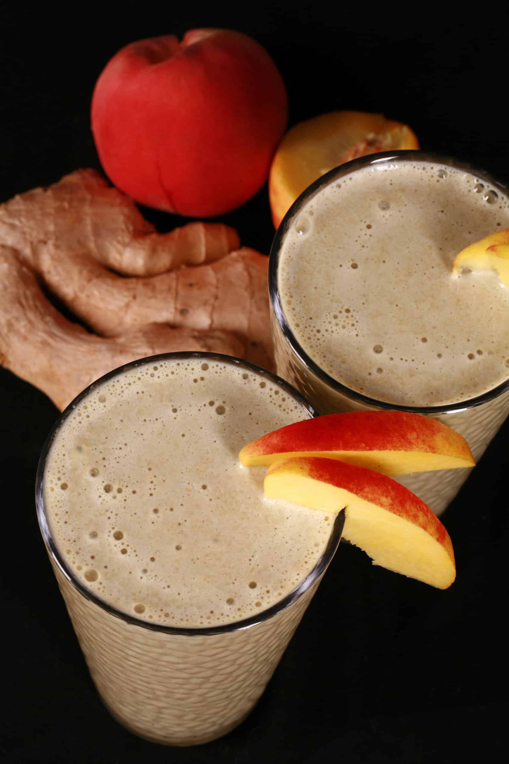 2 ginger high protein peach matcha smoothies, with fresh peaches and ginger root.
