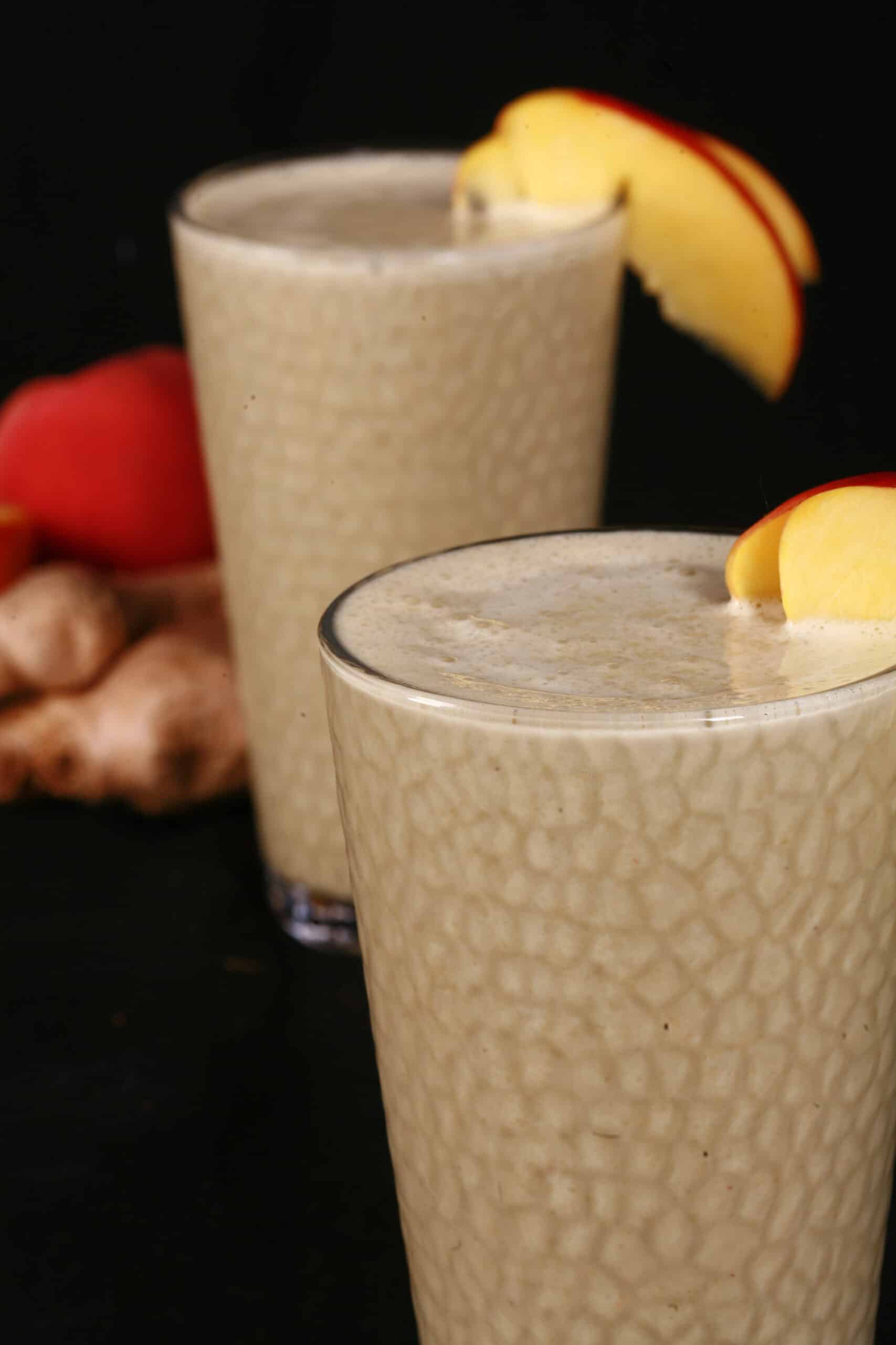 2 ginger high protein peach matcha smoothies, with fresh peaches and ginger root.