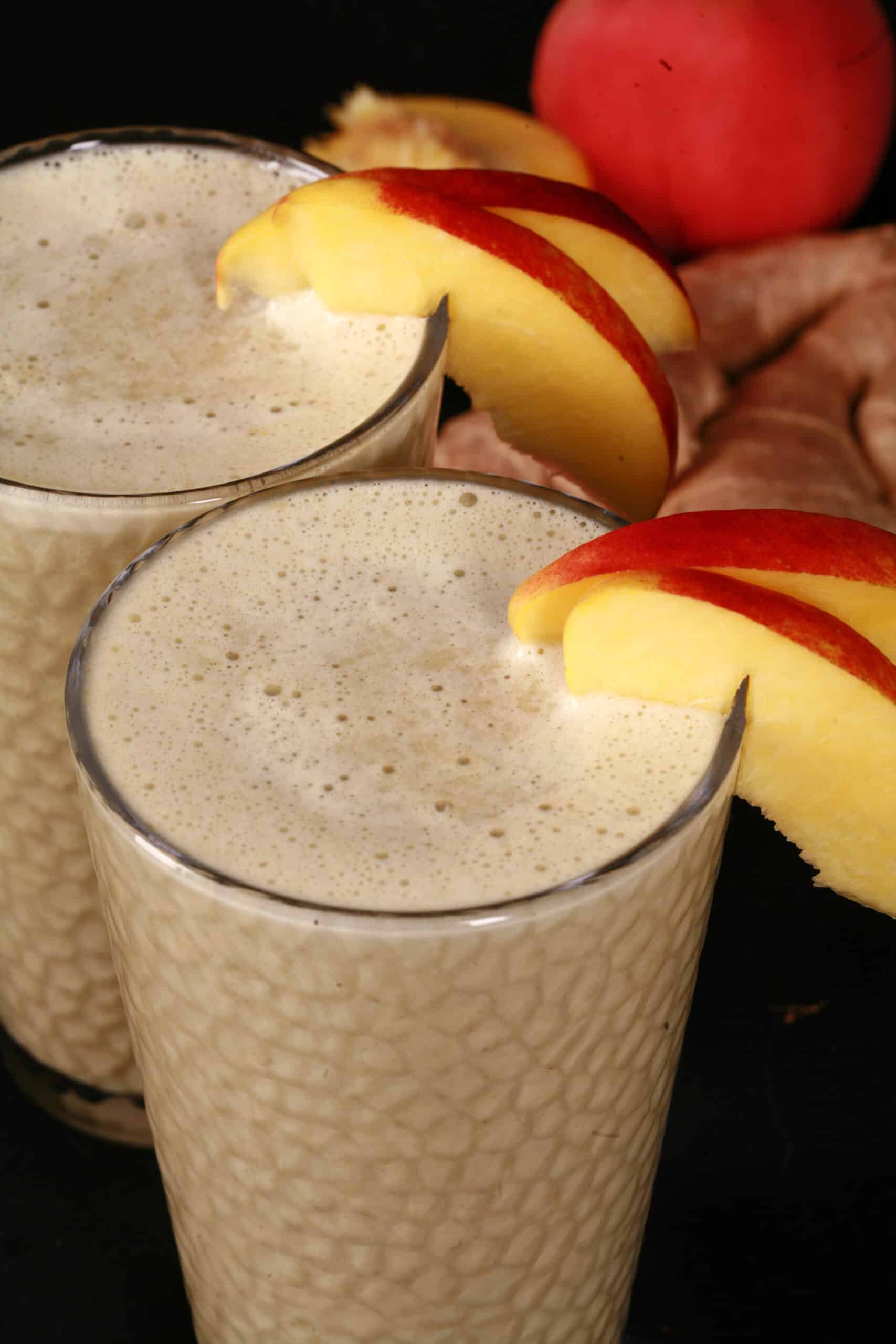 2 ginger peach matcha protein smoothies, with fresh peaches and ginger root.