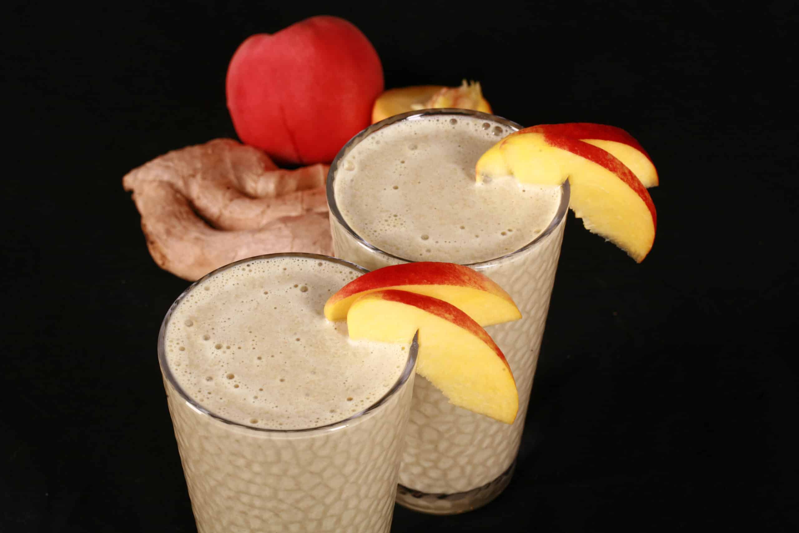 2 ginger high protein peach matcha smoothies, with fresh peaches and ginger root.